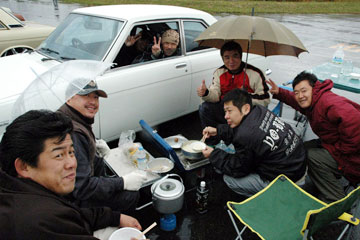大雨の中ラーメンを食らう男達